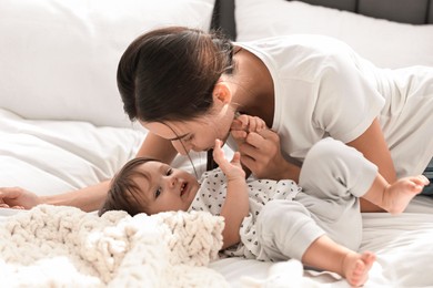 Photo of Beautiful young mother and her cute little baby on bed at home