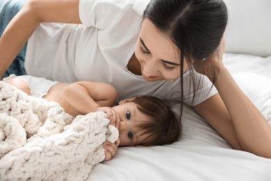 Beautiful young mother with her cute little baby on bed