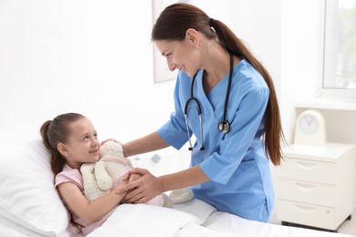 Photo of Doctor examining little girl on bed at hospital