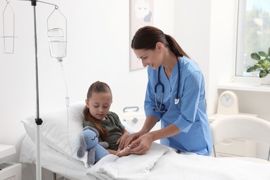 Doctor examining little girl on bed at hospital