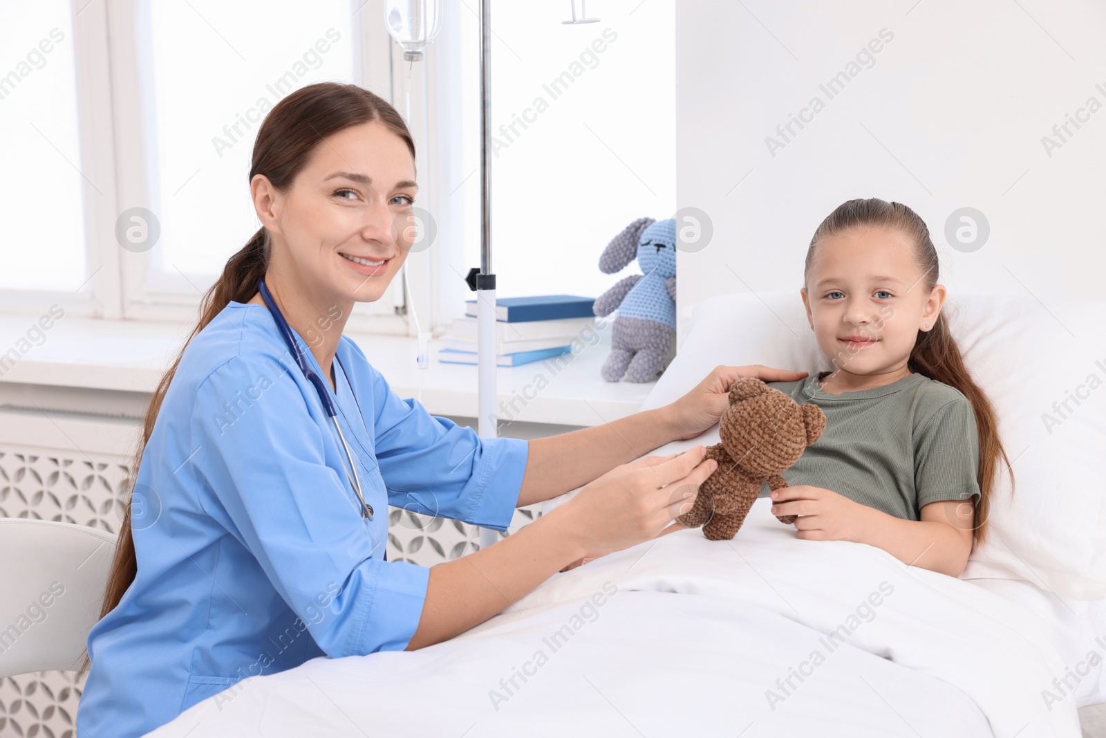 Photo of Doctor examining little girl on bed at hospital