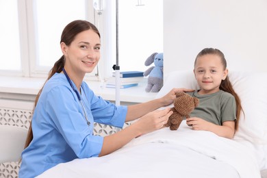 Doctor examining little girl on bed at hospital