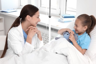 Photo of Doctor examining little girl on bed at hospital