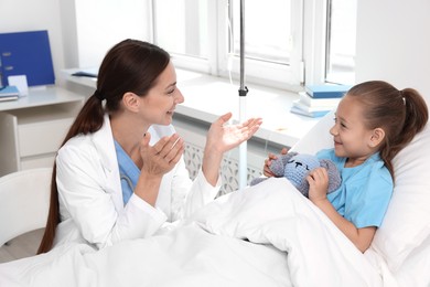 Doctor examining little girl on bed at hospital