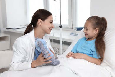 Photo of Doctor examining little girl on bed at hospital