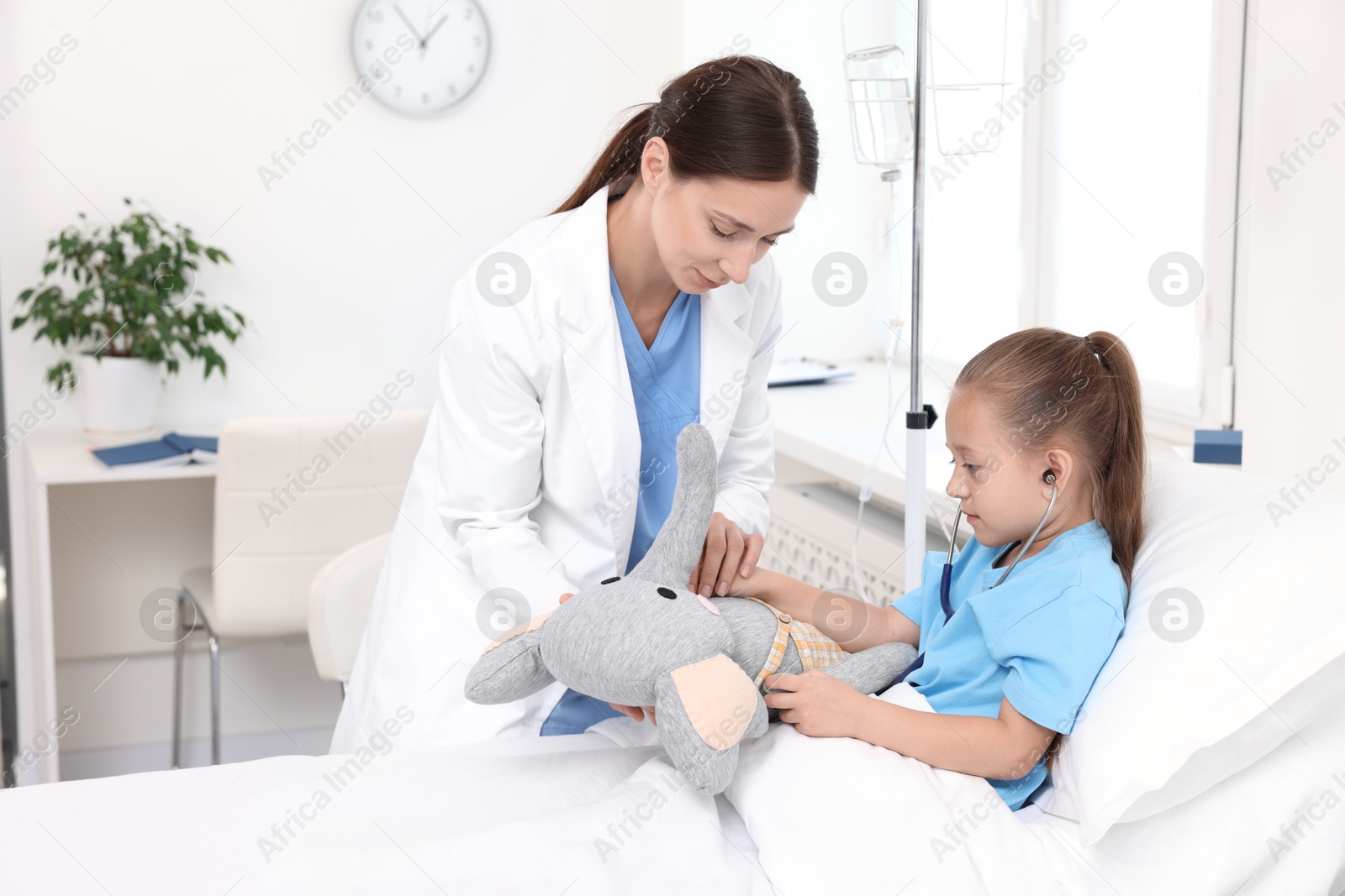 Photo of Doctor examining little girl on bed at hospital