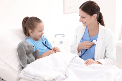 Photo of Doctor examining little girl on bed at hospital