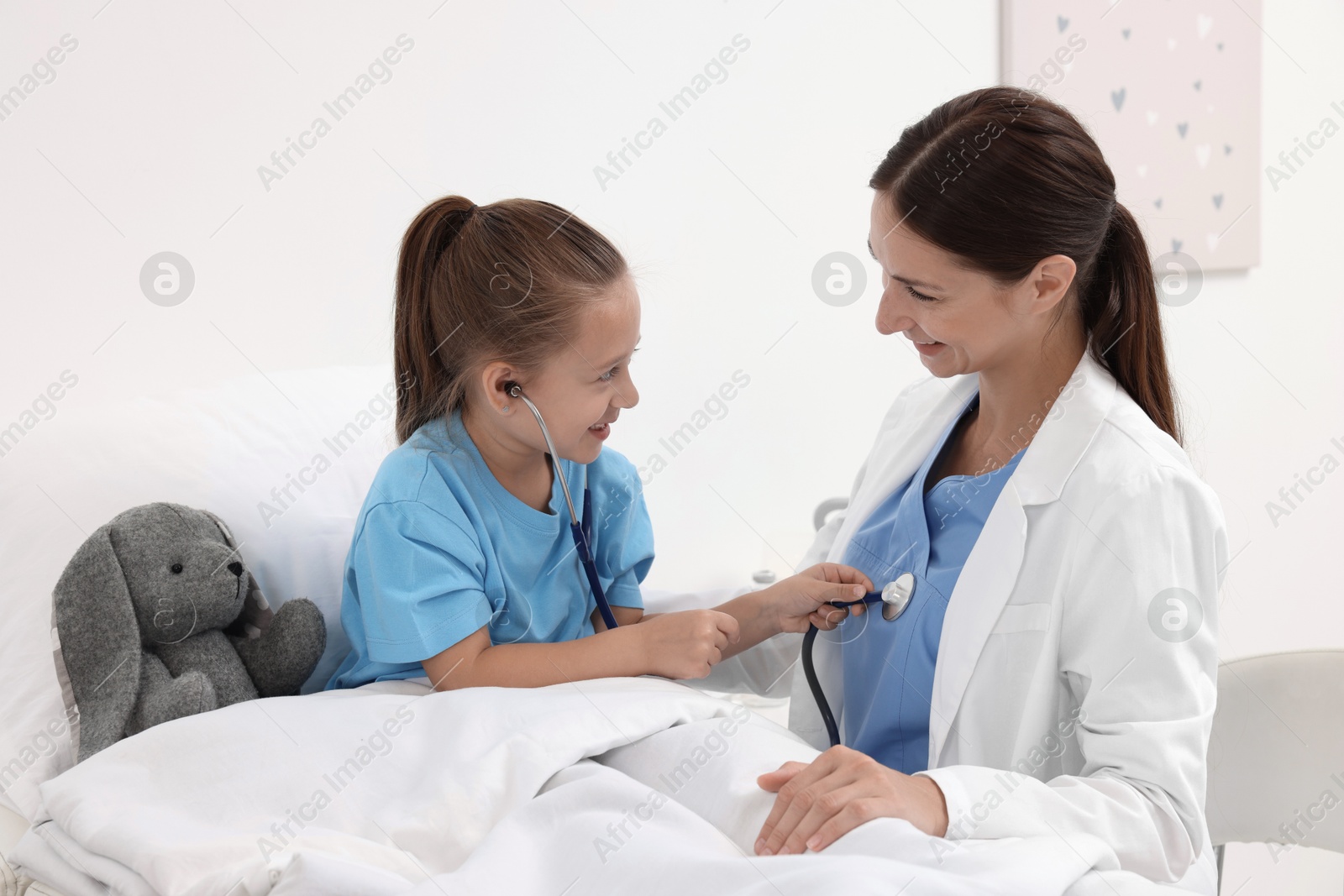 Photo of Doctor examining little girl on bed at hospital