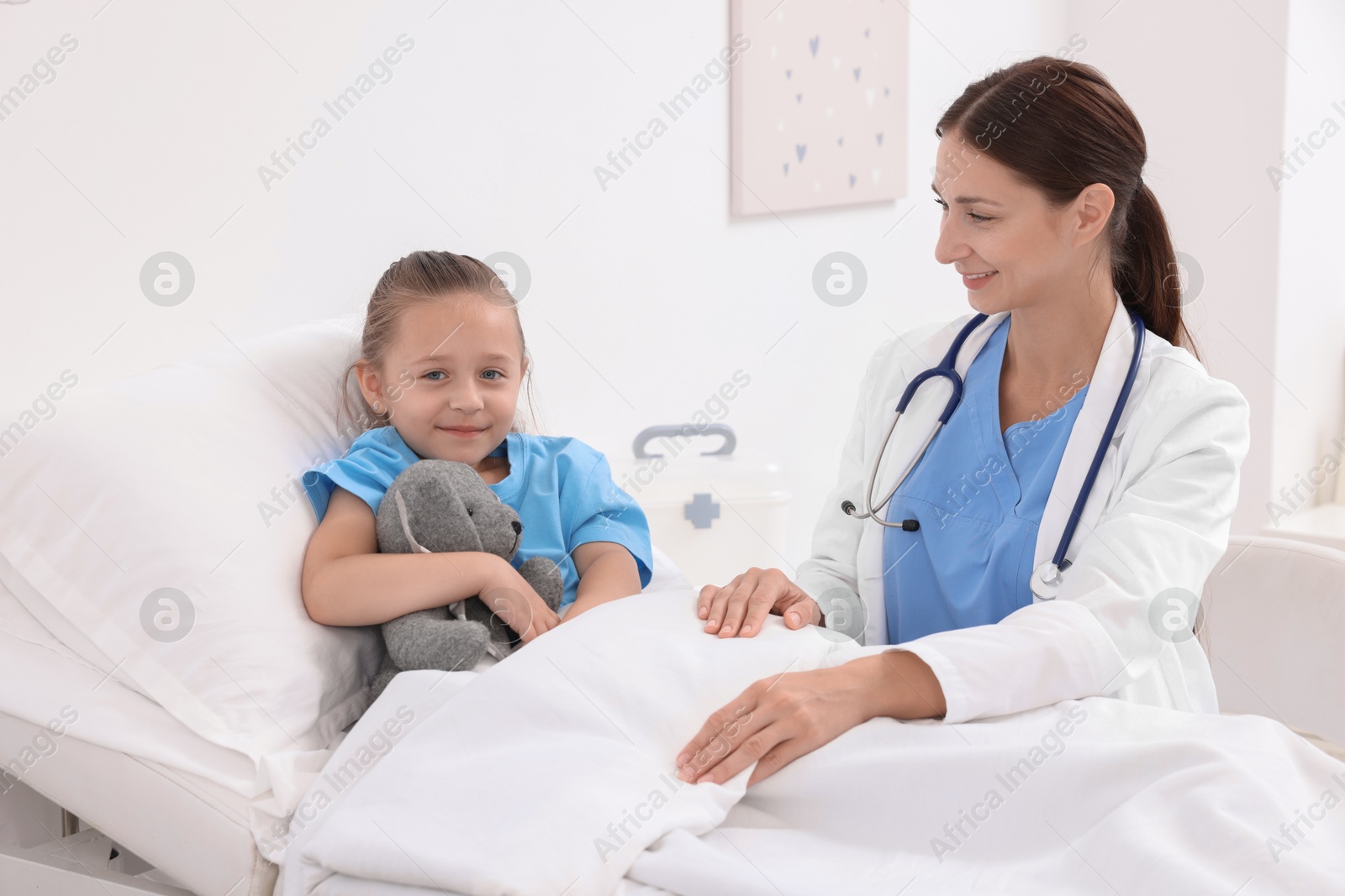 Photo of Doctor examining little girl on bed at hospital