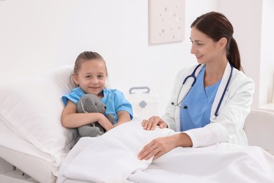 Photo of Doctor examining little girl on bed at hospital