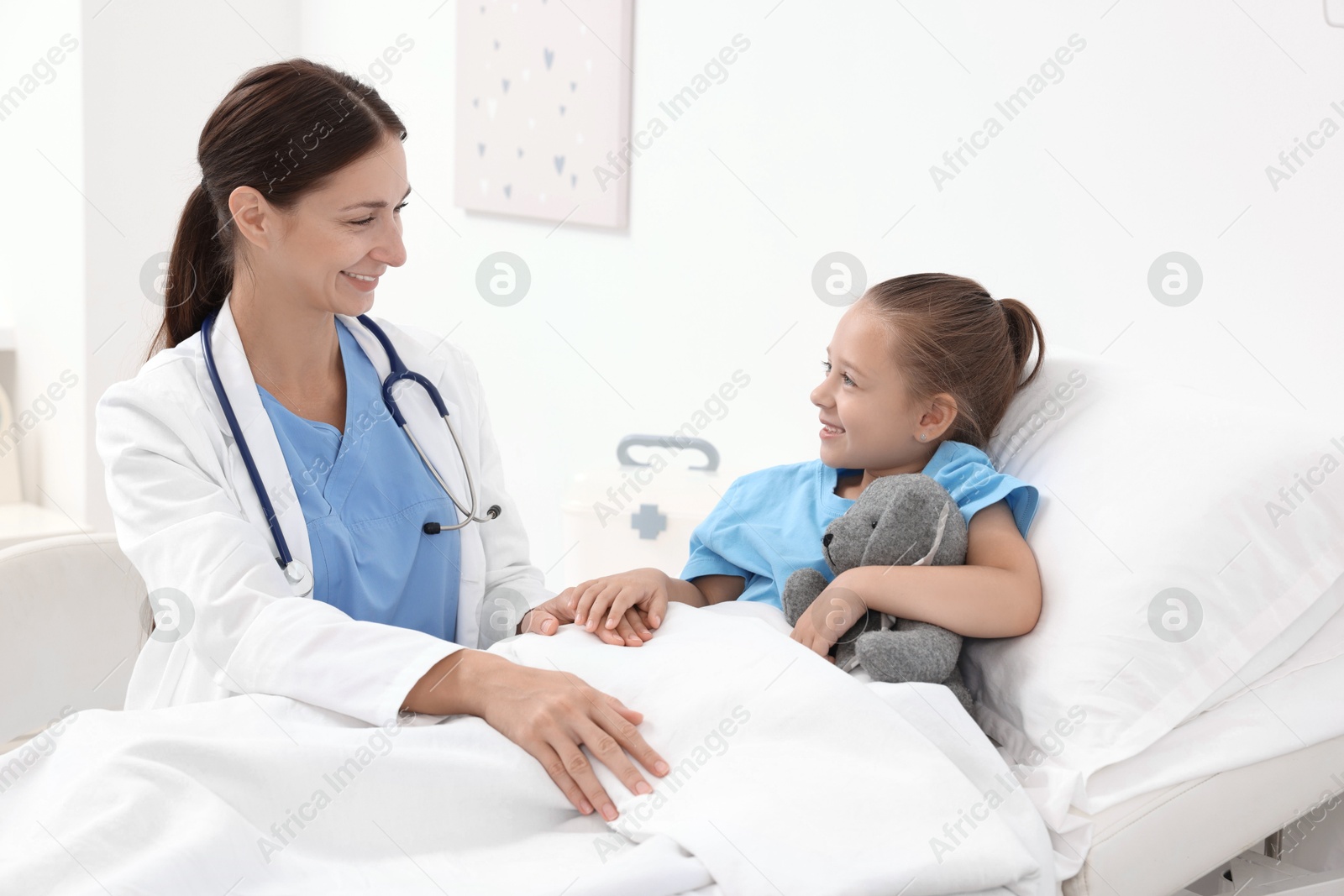 Photo of Doctor examining little girl on bed at hospital