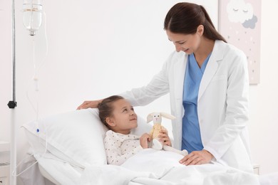 Photo of Doctor examining little girl on bed at hospital