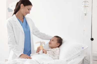 Doctor examining little girl on bed at hospital