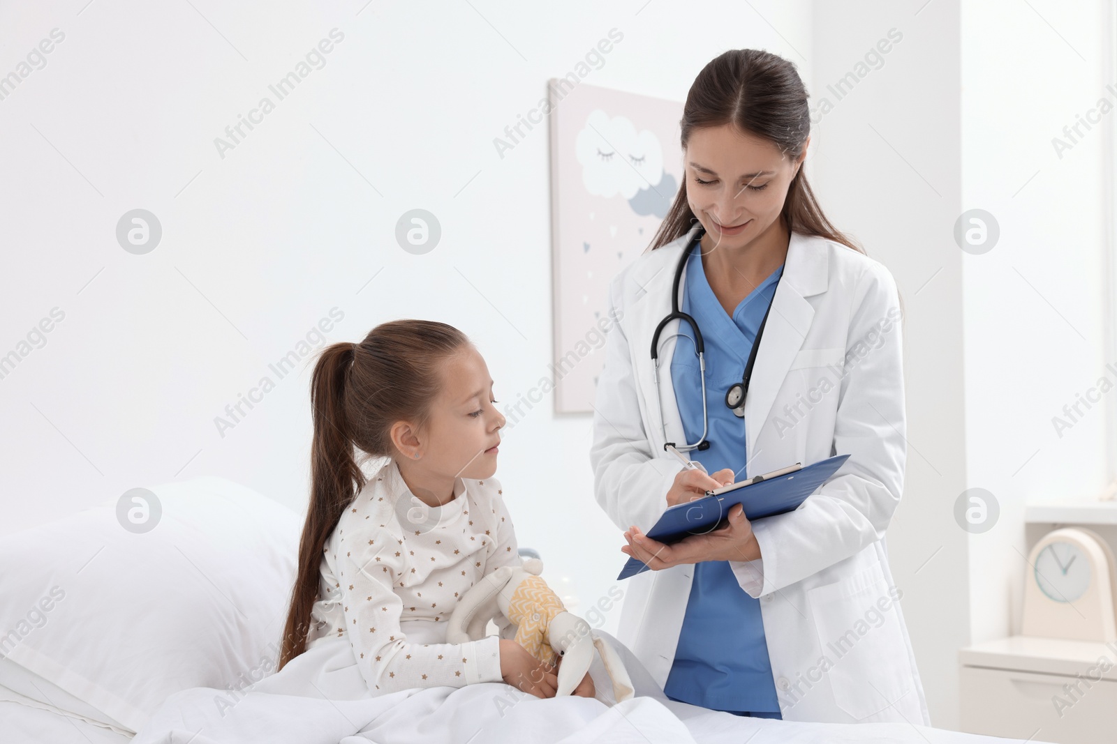 Photo of Doctor examining little girl on bed at hospital