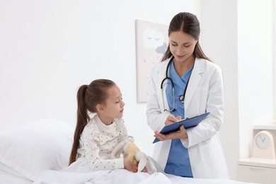 Doctor examining little girl on bed at hospital