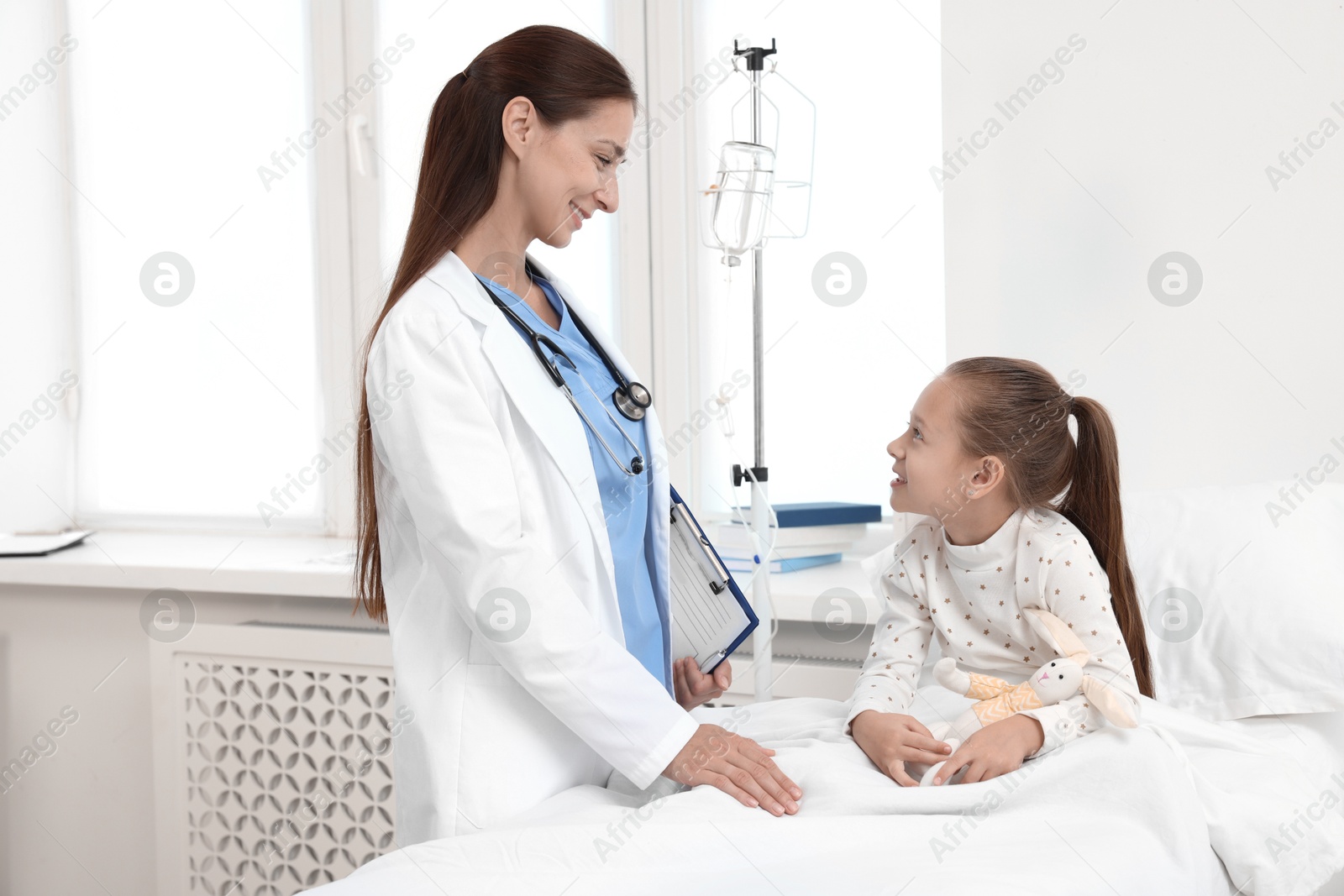 Photo of Doctor examining little girl on bed at hospital