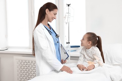 Doctor examining little girl on bed at hospital