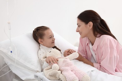 Mother and her little daughter on bed in hospital