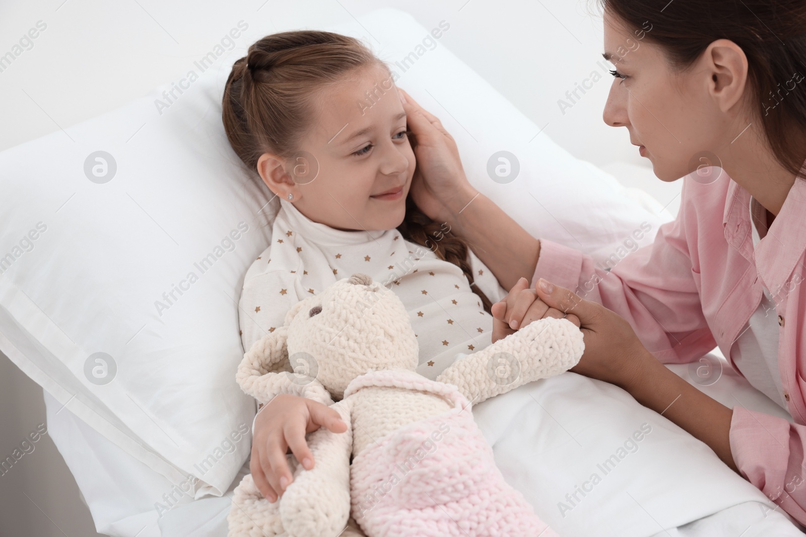 Photo of Mother and her little daughter on bed in hospital