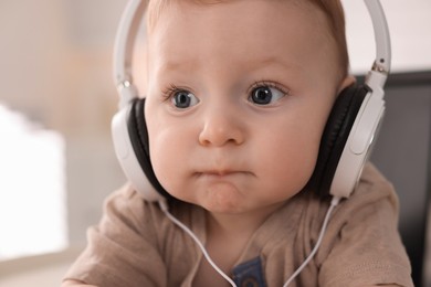 Photo of Cute little baby with headphones at home