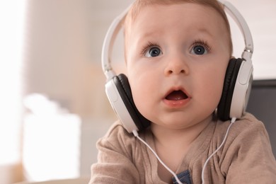 Photo of Cute little baby with headphones at home, space for text