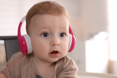 Photo of Cute little baby with headphones at home, space for text