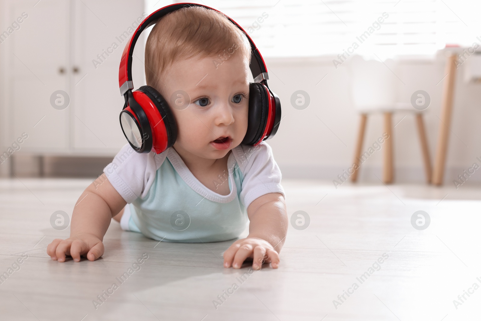 Photo of Cute little baby with headphones on floor at home, space for text