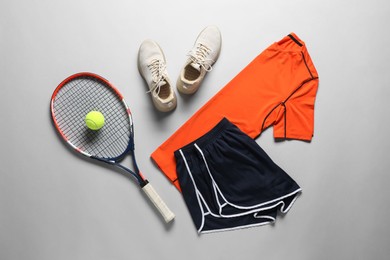 Photo of Tennis racket, ball, sneakers and sportswear on grey background, flat lay