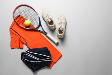 Photo of Tennis racket, ball, sneakers and sportswear on grey background, flat lay. Space for text