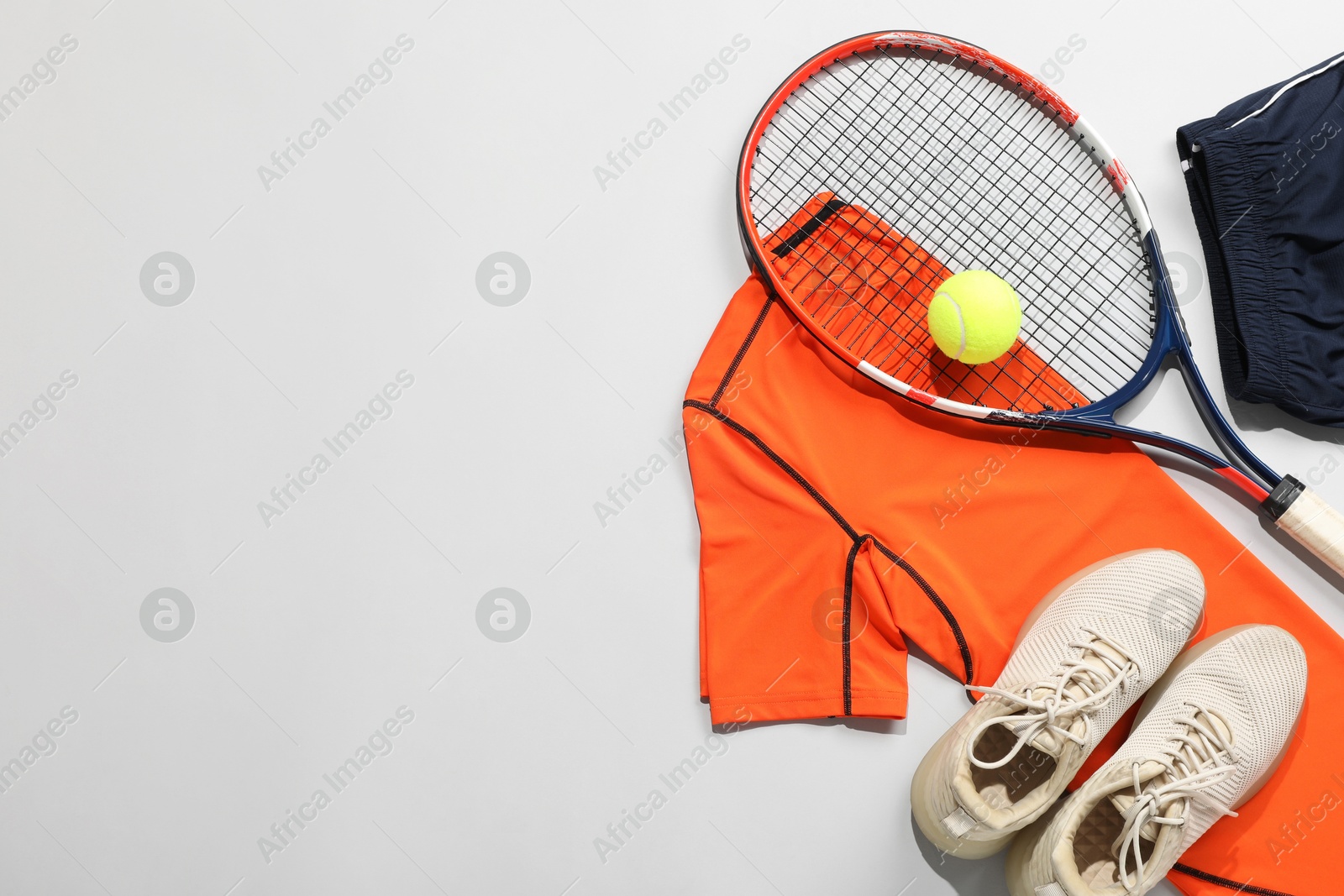 Photo of Tennis racket, ball, sneakers and sportswear on grey background, flat lay. Space for text