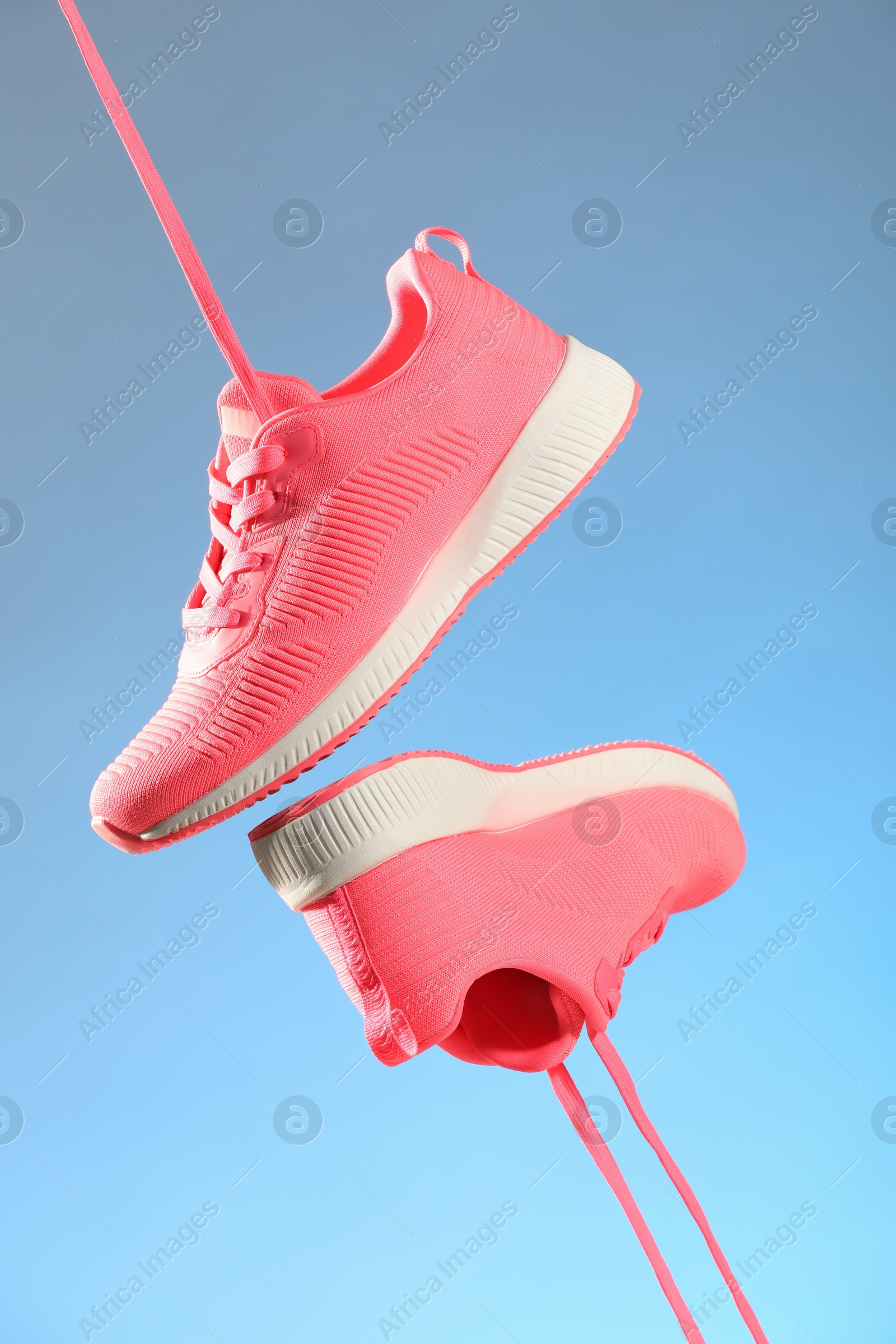 Photo of Pair of stylish sneakers in air against light blue background