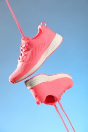 Pair of stylish sneakers in air against light blue background