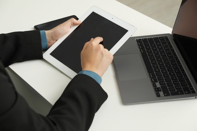 Photo of Businesswoman using tablet at white table indoors, closeup. Modern technology