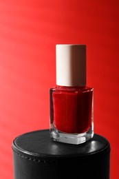 Photo of Nail polish in bottle on red background