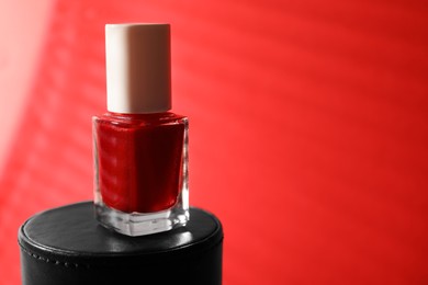 Photo of Nail polish in bottle on red background, space for text