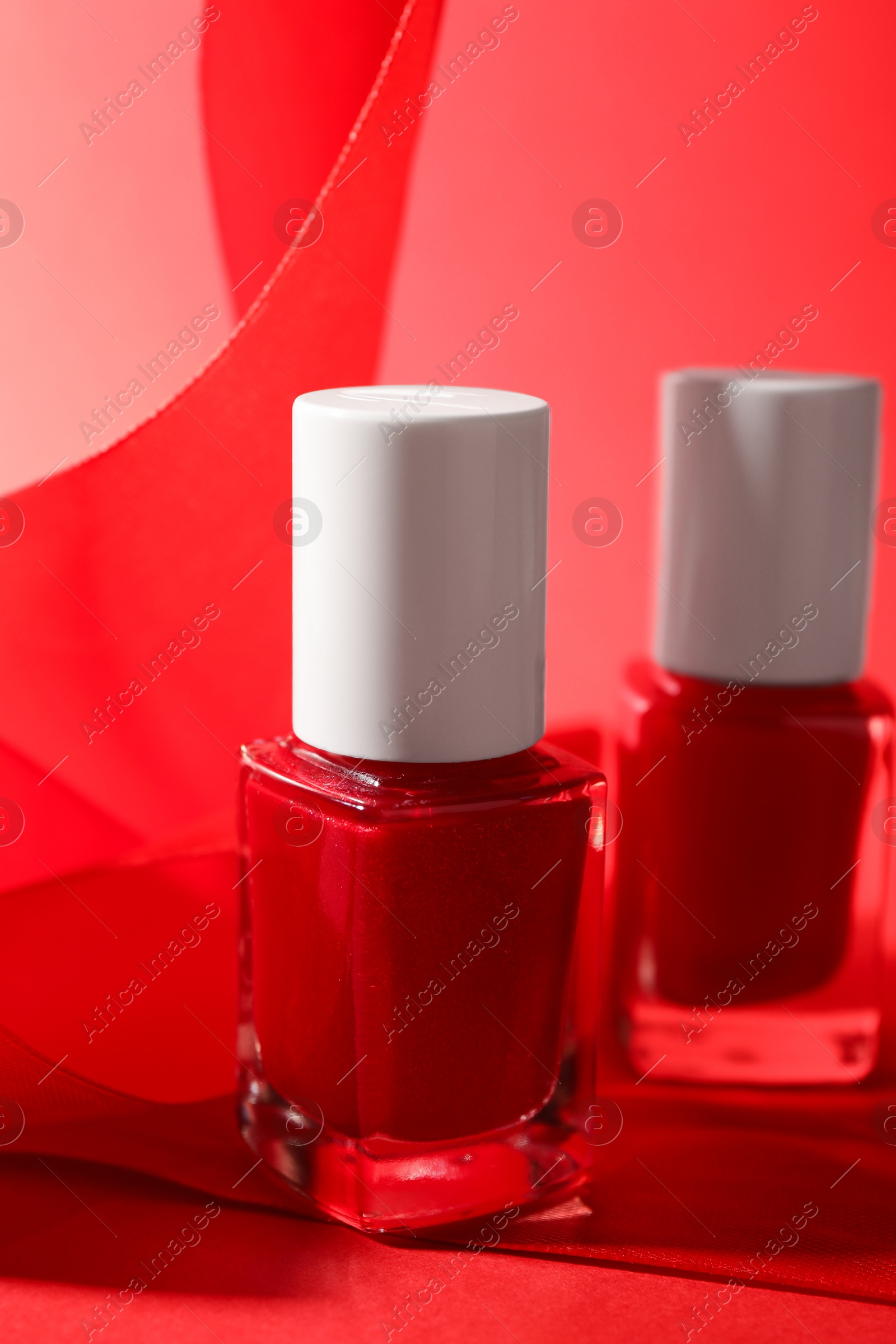 Photo of Nail polish in bottles on red background, closeup