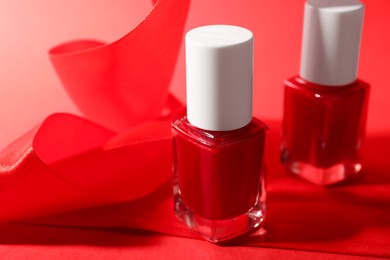 Photo of Nail polish in bottles on red background, closeup