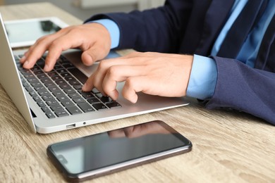 Photo of Businessman using laptop at wooden table, closeup. Modern technology