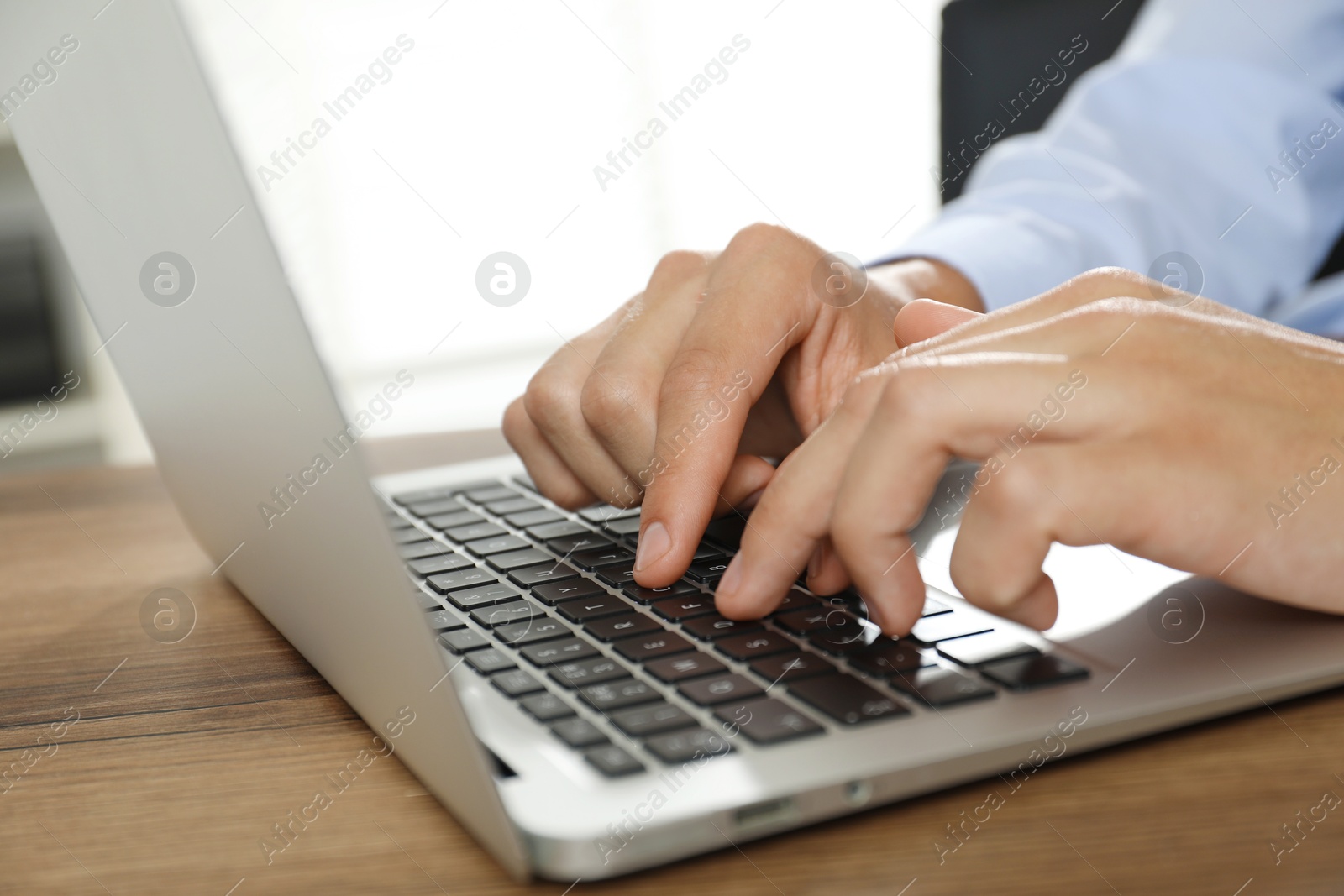 Photo of Businessman using laptop at wooden table, closeup. Modern technology