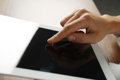 Photo of Businesswoman using tablet at table indoors, closeup. Modern technology