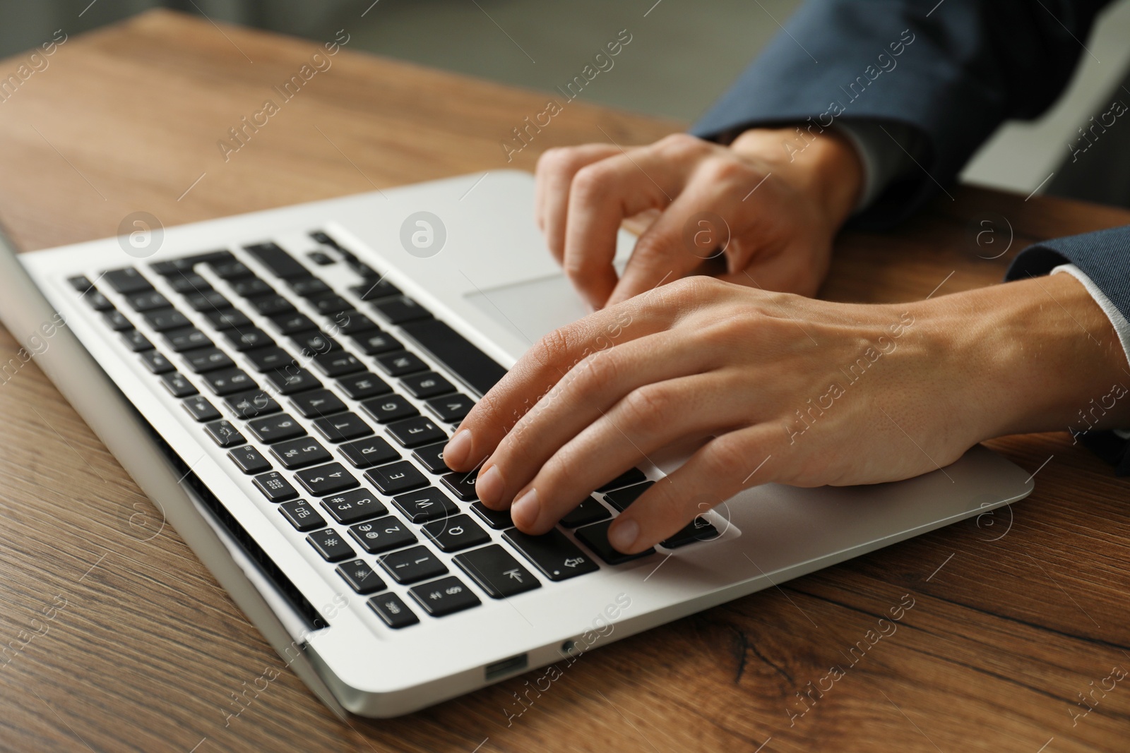 Photo of Businesswoman using laptop at wooden table indoors, closeup. Modern technology