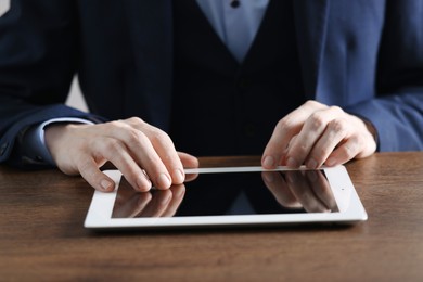 Photo of Businessman using tablet at wooden table, closeup. Modern technology