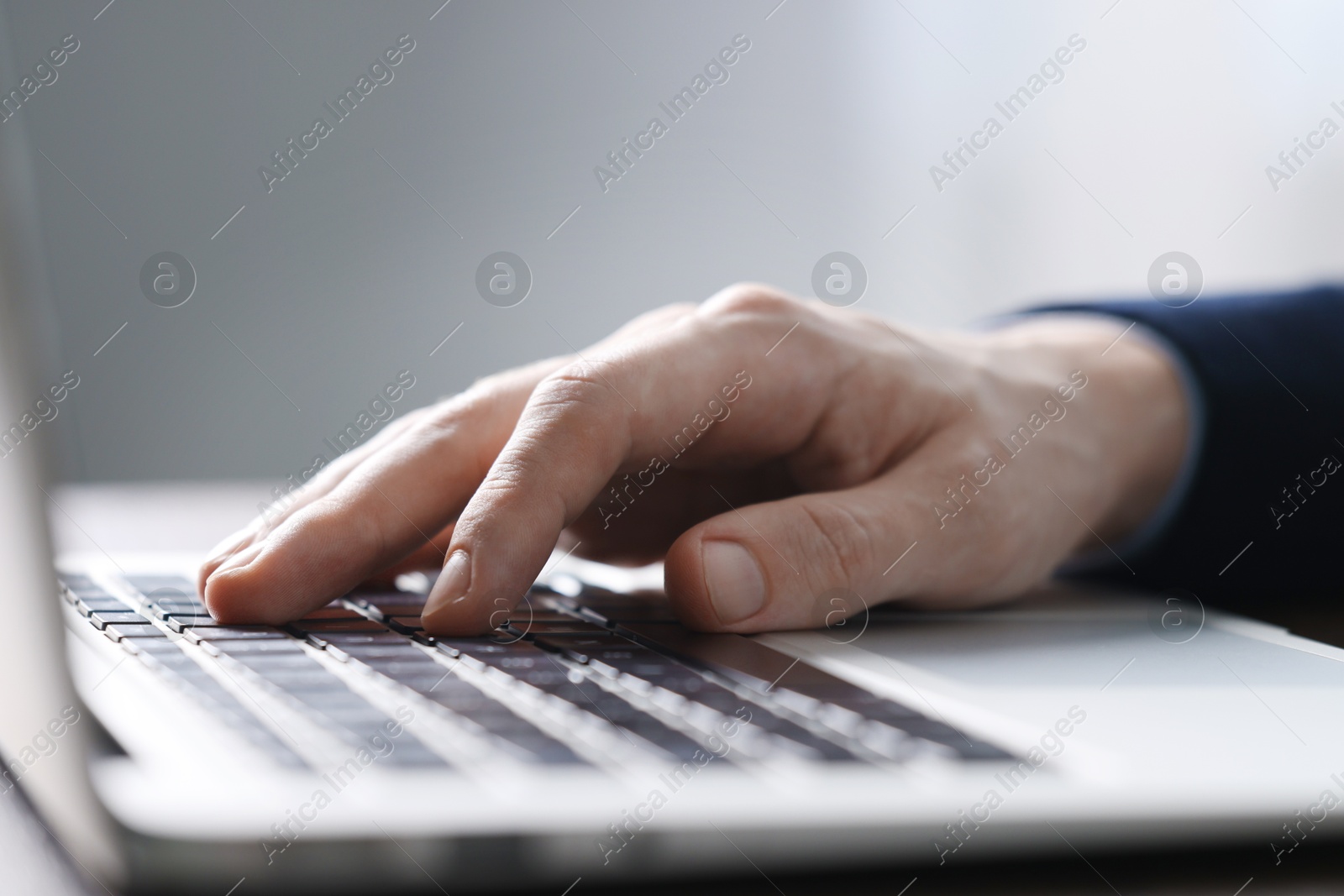 Photo of Businessman using laptop indoors, closeup. Modern technology