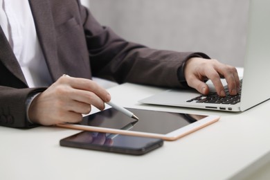 Photo of Businessman using different devices at white table indoors, closeup. Modern technology