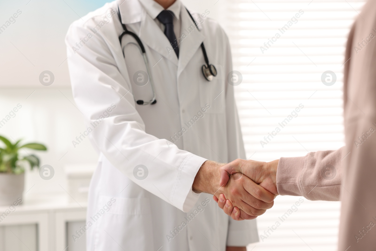 Photo of Doctor shaking hands with patient in hospital, closeup