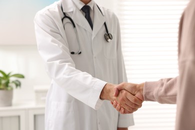 Doctor shaking hands with patient in hospital, closeup