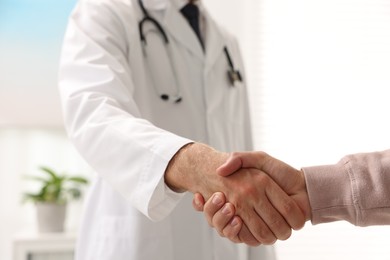 Doctor shaking hands with patient in hospital, closeup