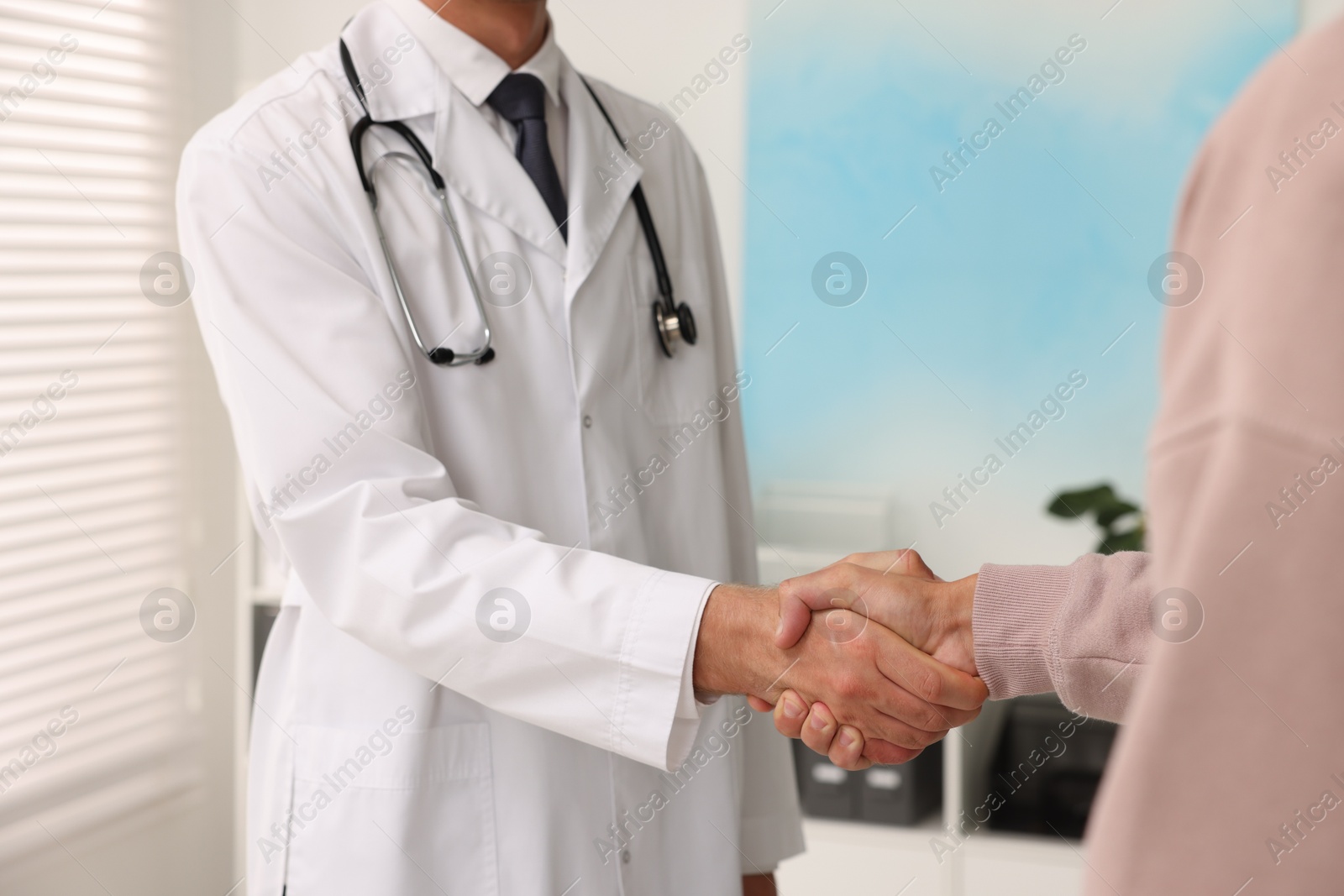 Photo of Doctor shaking hands with patient in hospital, closeup