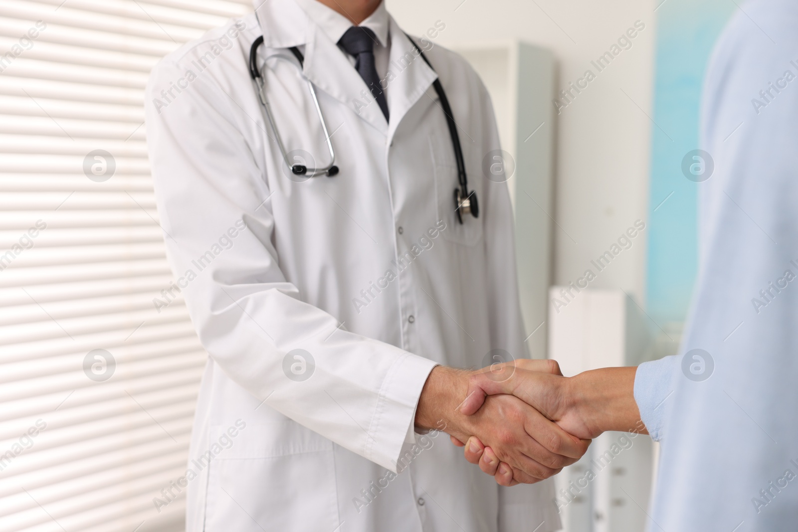 Photo of Doctor shaking hands with patient in hospital, closeup