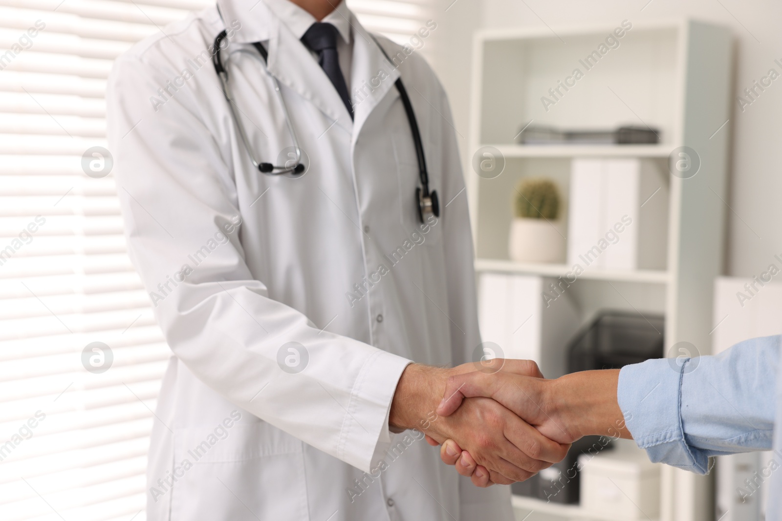 Photo of Doctor shaking hands with patient in hospital, closeup